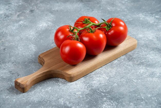 Tomates rojos frescos sobre tabla de madera.