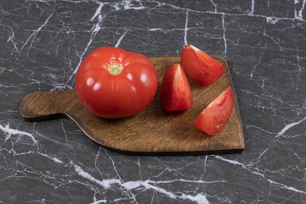 Tomates rojos frescos sobre tabla de madera.