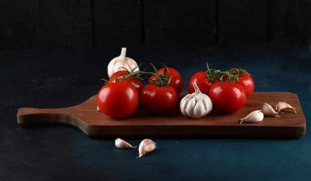 Tomates rojos y guantes de ajo en el tablero de madera.