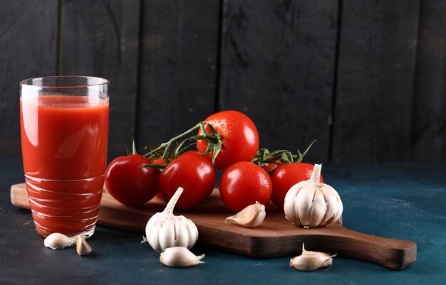 Tomates rojos, guantes de ajo y un vaso de jugo de tomate.
