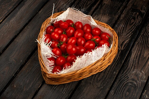 Tomates rojos maduros dentro de la cesta en la madera marrón