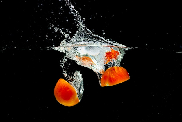 Tomates rojos mitades chapoteando en agua dulce