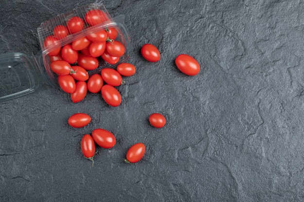 Tomates rojos pequeños orgánicos frescos sobre fondo negro. Foto de alta calidad