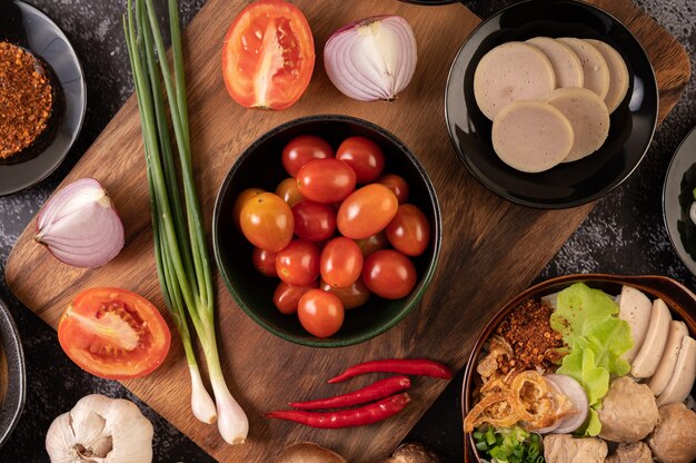 Los tomates en la taza negra con cebolletas, pimientos, tomates y cebollas rojas.