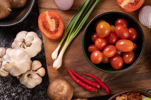 Los tomates en la taza negra con cebolletas, pimientos, tomates y cebollas rojas.