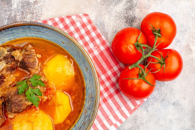 Tomates de toalla de cocina de sopa bozbash casera de vista superior en superficie desnuda