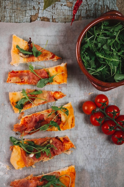 Tomates y vegetación cerca de la pizza