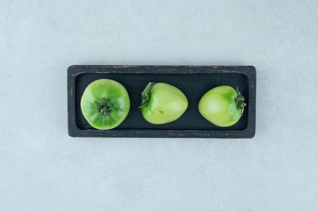 Tomates verdes en escabeche en placa negra.