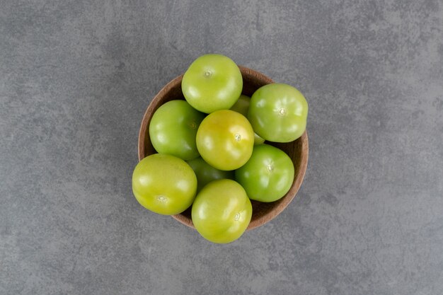 Tomates verdes frescos en un tazón de madera. Foto de alta calidad