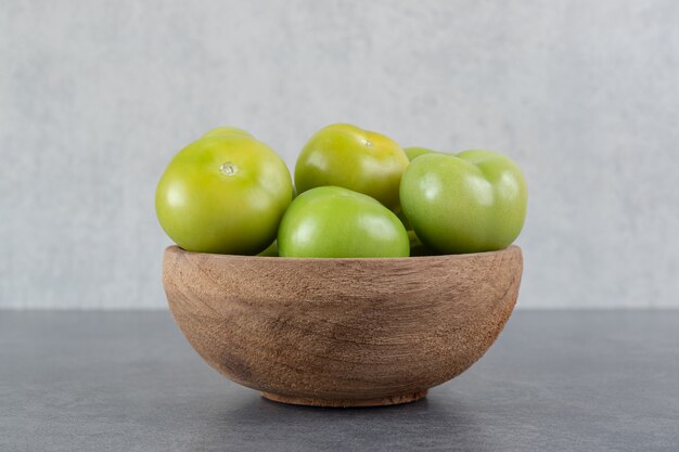 Tomates verdes frescos en un tazón de madera. Foto de alta calidad