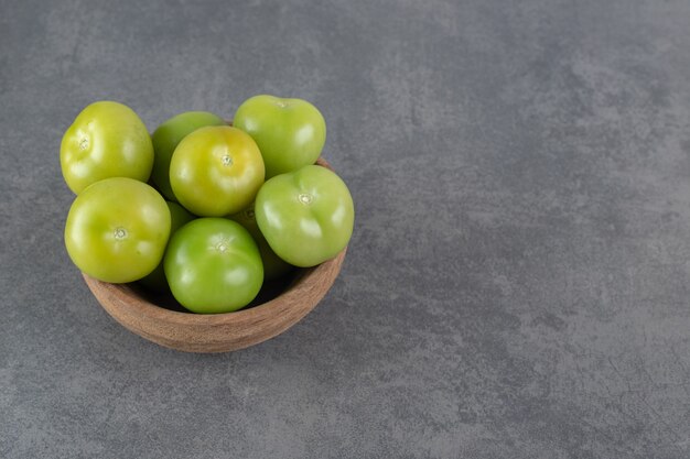 Tomates verdes frescos en un tazón de madera. Foto de alta calidad