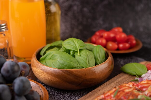 Tomillo y tomates en una taza de madera con ajo en una tabla de cortar de madera.