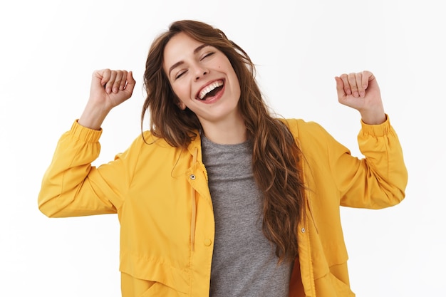 Tonta linda mujer europea bostezando con las manos levantadas estirando el cuerpo se siente energizado al despertar por la tarde de pie pared blanca soñolienta