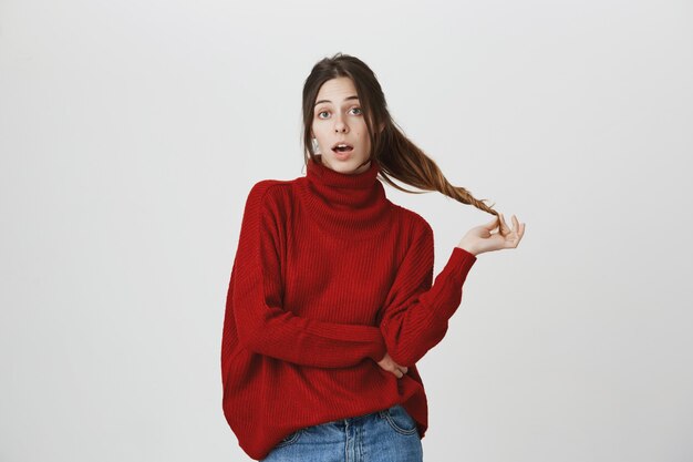 Tonta mujer joven sin problemas jugando con el pelo, conversa