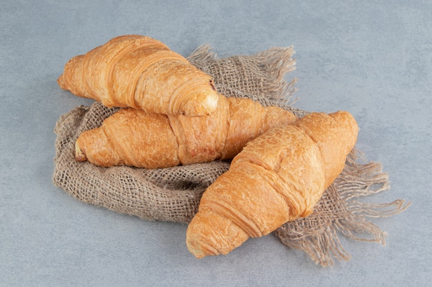 Toothsome croissant en toalla, sobre el fondo de mármol. Foto de alta calidad