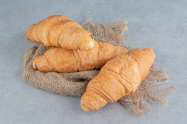 Toothsome croissant en toalla, sobre el fondo de mármol. Foto de alta calidad
