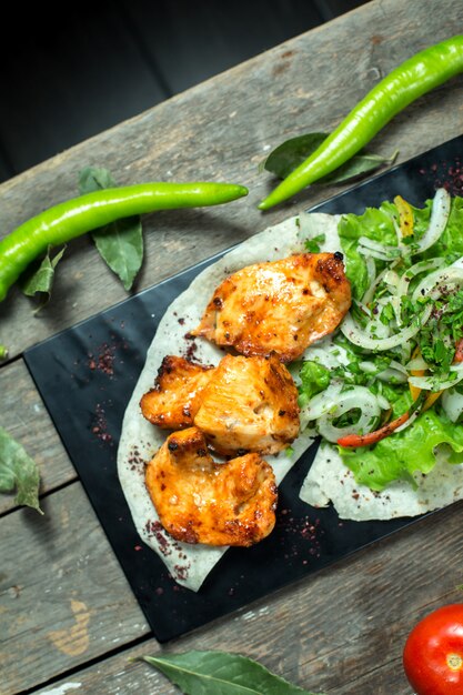 top kebab de pollo servido con cebolla tomate a la parrilla y pimiento en pizarra