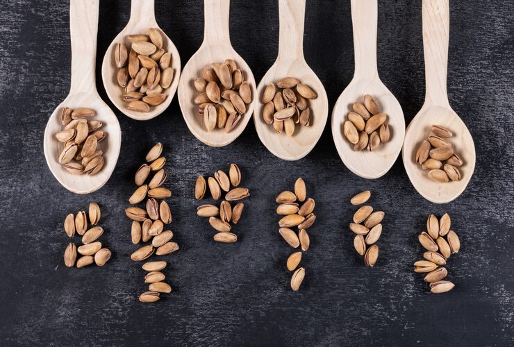 Photo Gratis top view of pistachios on wooden spoons on dark  horizontal
