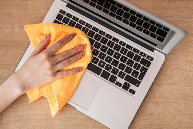 top view of woman cleaning laptop with cloth
