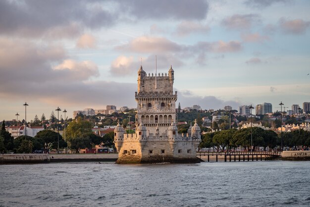 Torre de Belem rodeada por el mar y edificios bajo un cielo nublado en Portugal