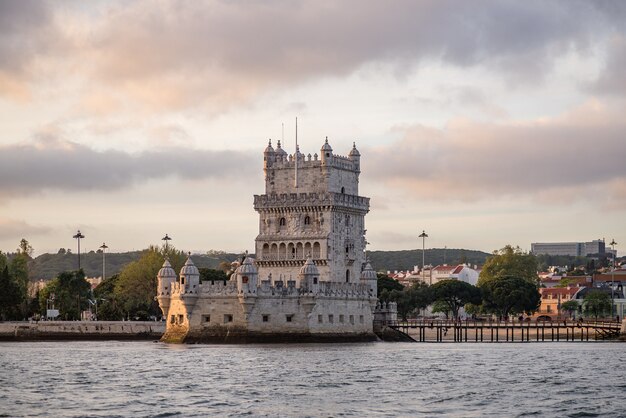 Torre de Belem rodeada por el mar y edificios bajo un cielo nublado en Portugal