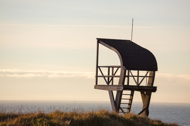 Torre de salvavidas en un campo rodeado por el mar bajo un cielo nublado en la noche