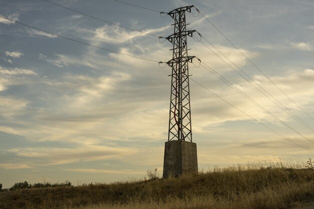 Torre de transmisión eléctrica de alta tensión contra el cielo al amanecer.