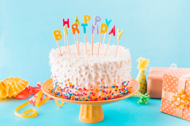 Foto gratuita torta de cumpleaños con regalo y accesorios sobre fondo azul