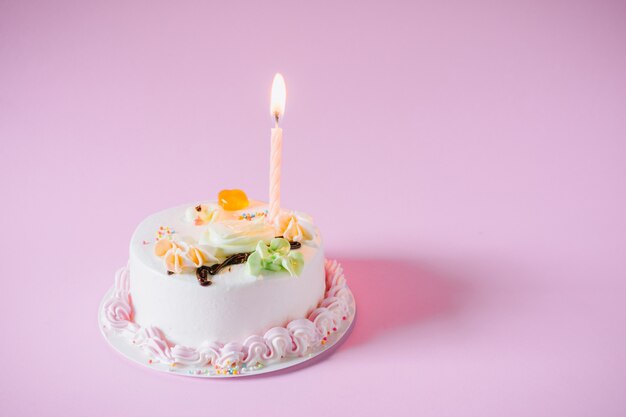 Torta de cumpleaños con velas sobre fondo de color