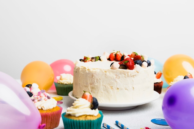 Torta grande con diferentes bayas cerca de globos de aire