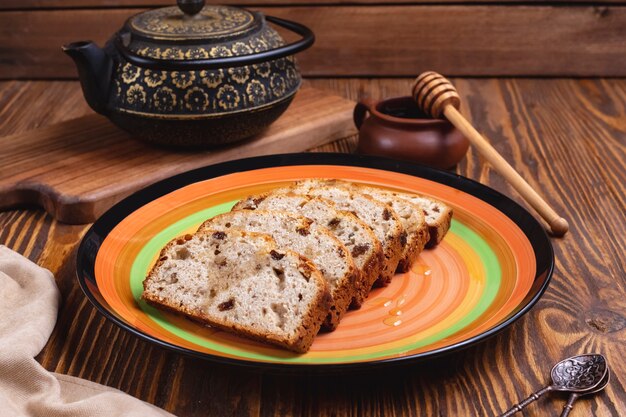 Torta inglesa de pasas de miel y una olla de té vista lateral