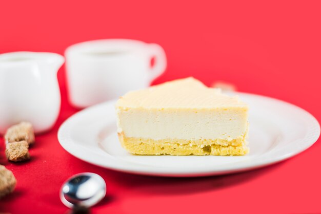 Torta de queso fresco en la placa blanca contra fondo rojo