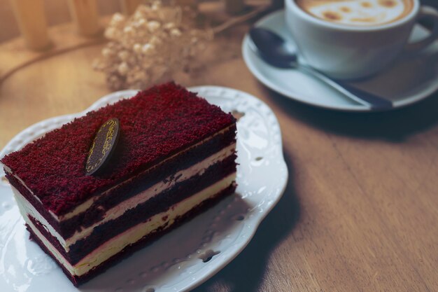 Torta de terciopelo rojo con taza de café caliente en la mesa de madera