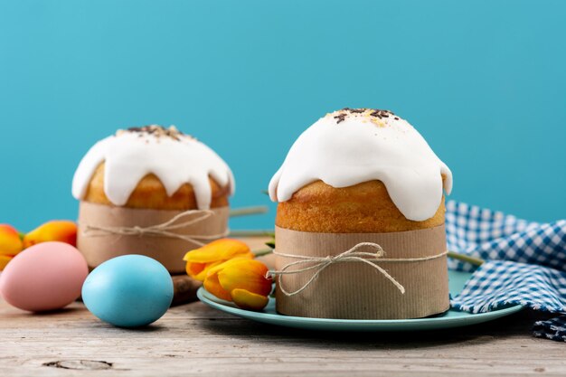 Torta tradicional de Pascua, huevos coloridos y tulipanes en mesa de madera