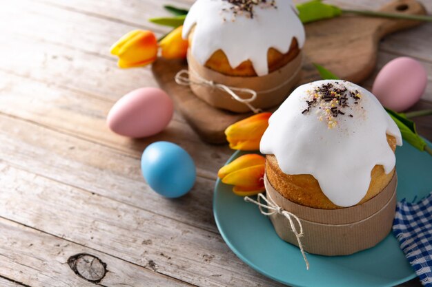 Torta tradicional de Pascua, huevos coloridos y tulipanes en mesa de madera