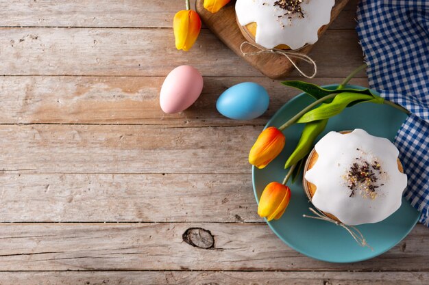 Torta tradicional de Pascua, huevos coloridos y tulipanes en mesa de madera