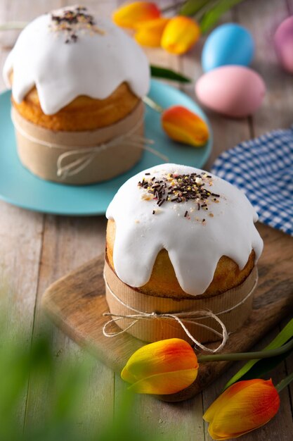 Torta tradicional de Pascua, huevos coloridos y tulipanes en mesa de madera