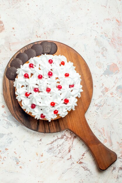 Torta de vista superior con chocolate y crema pastelera blanca sobre tabla de cortar de madera