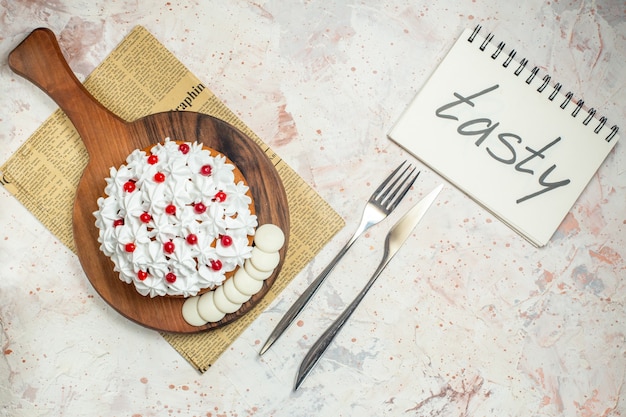 Torta de vista superior con crema pastelera blanca sobre tabla de cortar. sabroso escrito en el cuaderno