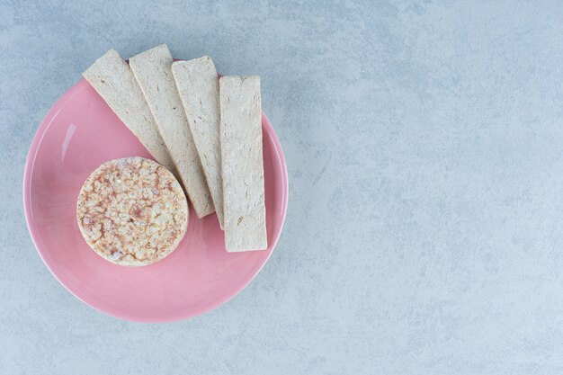 Tortas de arroz inflado y galleta dulce en el plato sobre mármol.