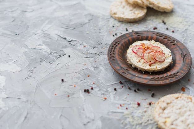 Tortas de arroz originales adornadas con un pequeño trozo de nabo y queso sobre fondo gris texturizado