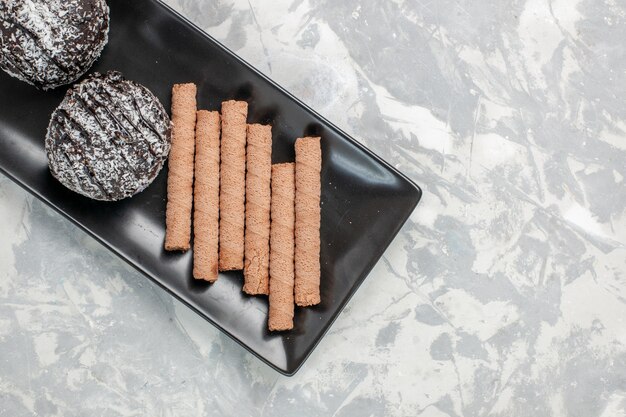 Tortas de chocolate de vista superior con galletas de pipa dulce dentro de la placa negra sobre superficie blanca