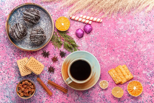 Tortas de chocolate de vista superior con gofres y taza de té en rosa