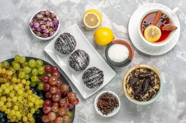 Tortas de chocolate de vista superior con uvas de limón y té sobre superficie blanca