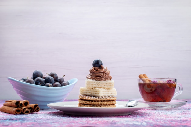 Tortas de gofres de vista frontal con uvas canela y té en gris