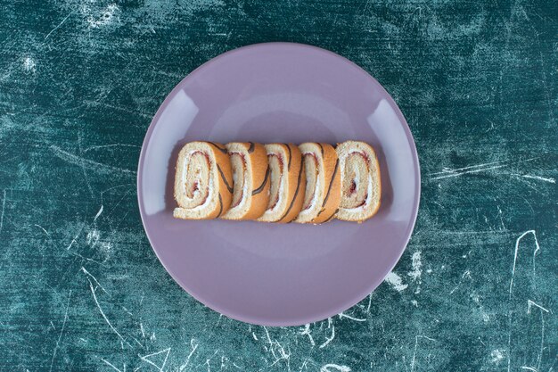 Tortas de rollo en rodajas en un plato, sobre el fondo azul. Foto de alta calidad