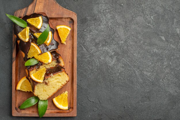 Tortas suaves naranjas enteras y cortadas con hojas sobre mesa oscura