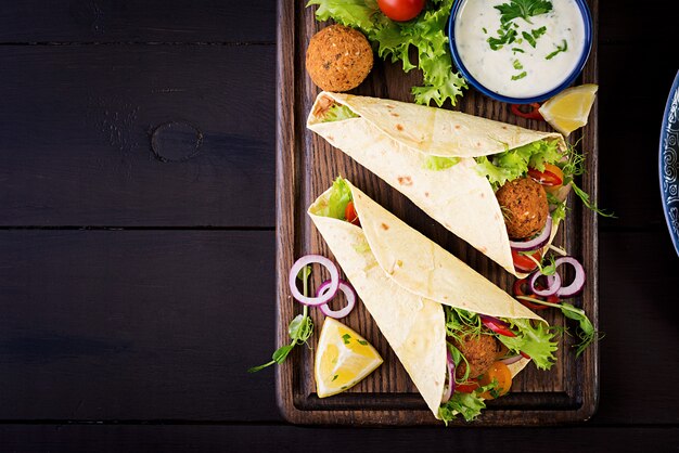 Tortilla envuelta con falafel y ensalada fresca. Tacos veganos. Comida vegetariana saludable. Vista superior