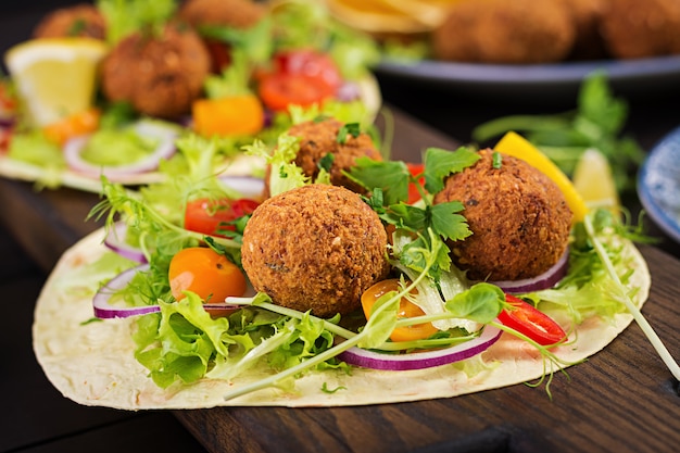 Tortilla envuelta con falafel y ensalada fresca. Tacos veganos. Comida vegetariana saludable.