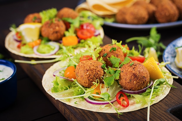 Tortilla envuelta con falafel y ensalada fresca. Tacos veganos. Comida vegetariana saludable.